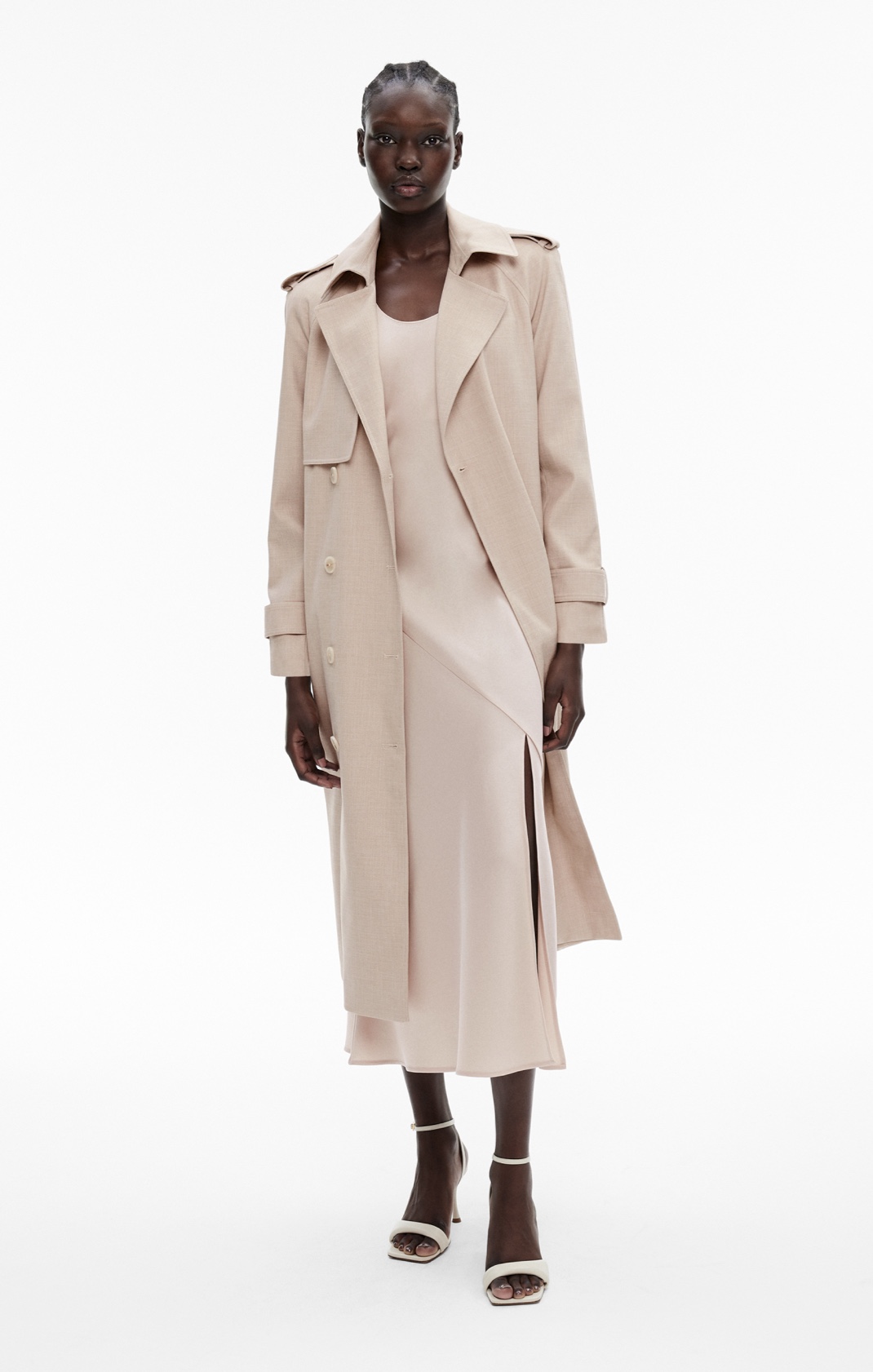 Woman in beige trench cpat amd cream satin slip dress