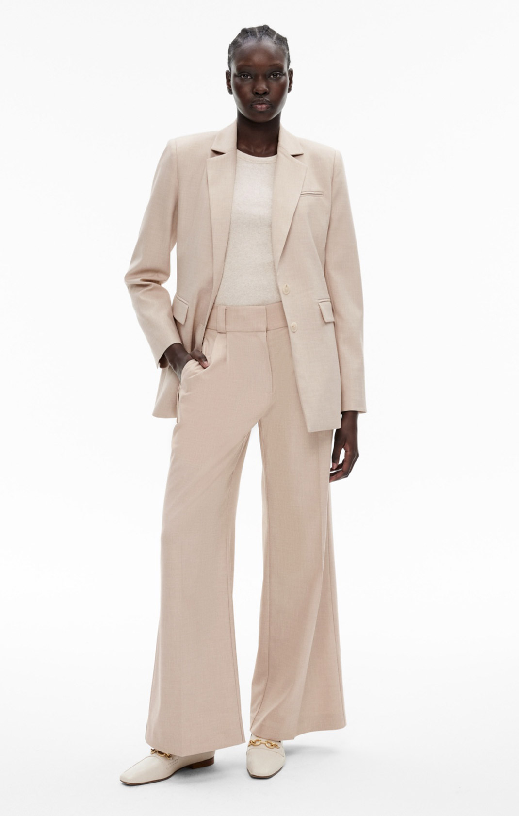 Woman in cream blazer, cream tank top, cream pants and white leather loafers