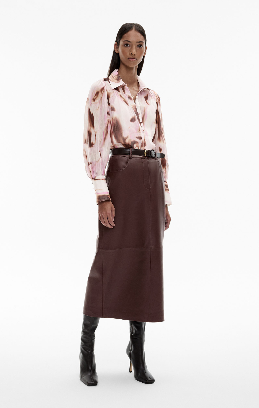 Woman in print long sleeve shirt, brown leather denim midi skirt, black leather boots and black leather belt