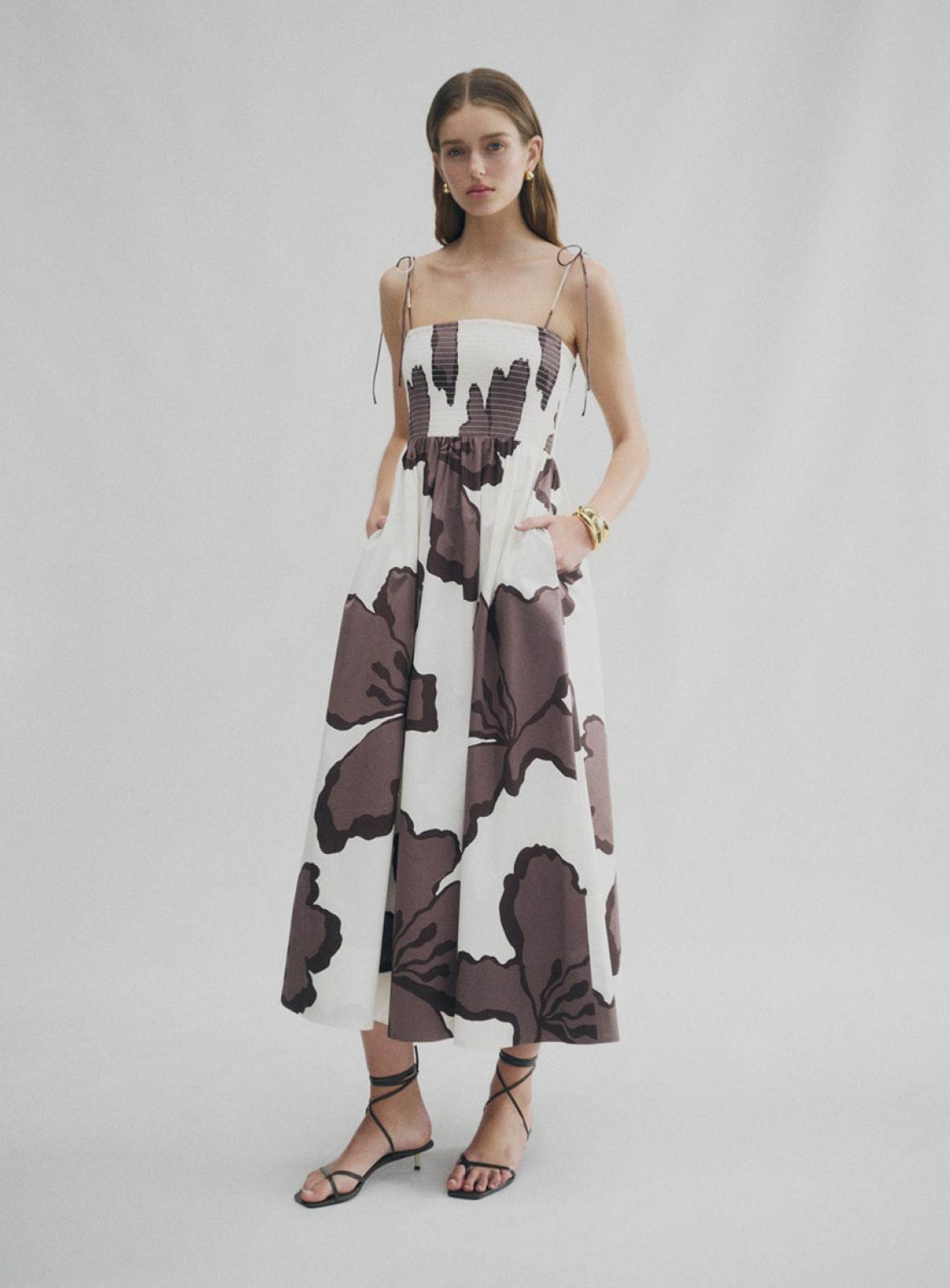 Woman in shirred print maxi dress, blair tie up heel and gold charlie huggie earrings